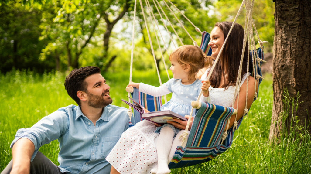 Zu sehen ist eine Familie mit einem Hängesessel im Garten